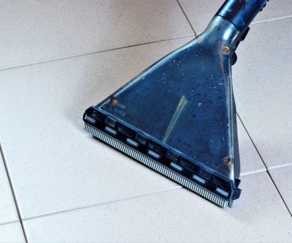 Cleaning tile floor surface wet vacuum, sanitary restoring clean of debris. Maintain safe hygiene cleanliness, remove dirt in industrial, office, and home.